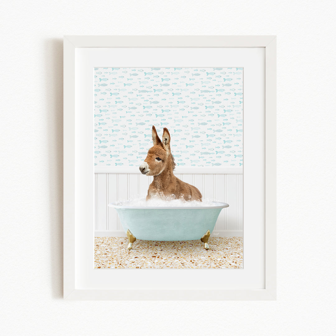 A donkey is sitting in a blue bathtub filled with bubbles, surrounded by a patterned wall and a beige floor.