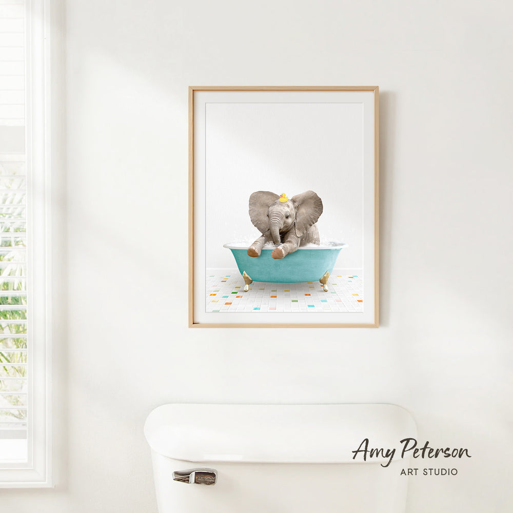 A framed image of a baby elephant sitting in a bathtub, with colorful confetti on the floor.