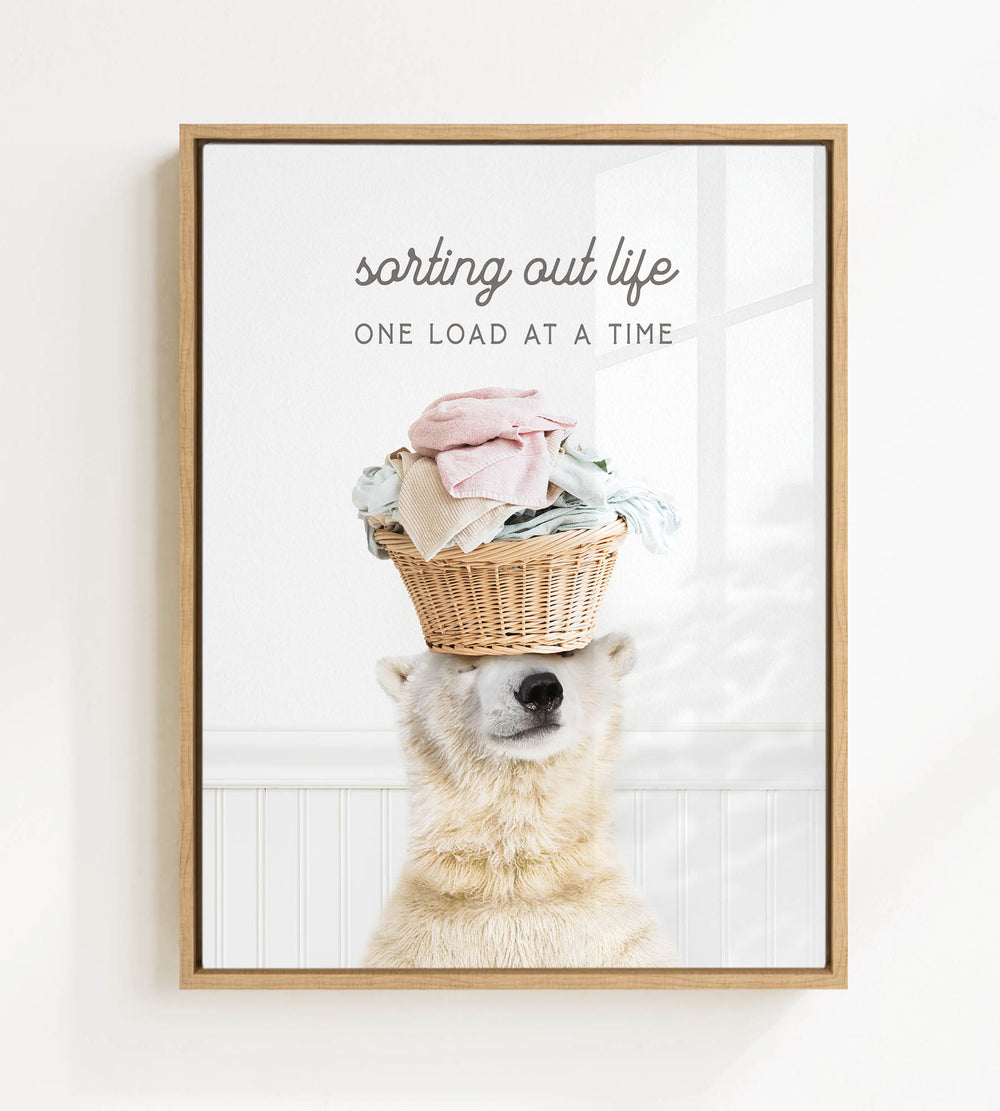 A polar bear balancing a basket of laundry on its head, with the text "sorting out life" and "ONE LOAD AT A TIME" displayed above the image.