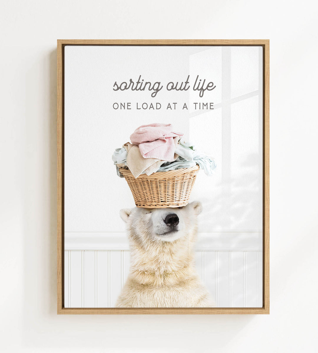 A polar bear balancing a basket of laundry on its head, with the text "sorting out life" and "ONE LOAD AT A TIME" displayed above the image.