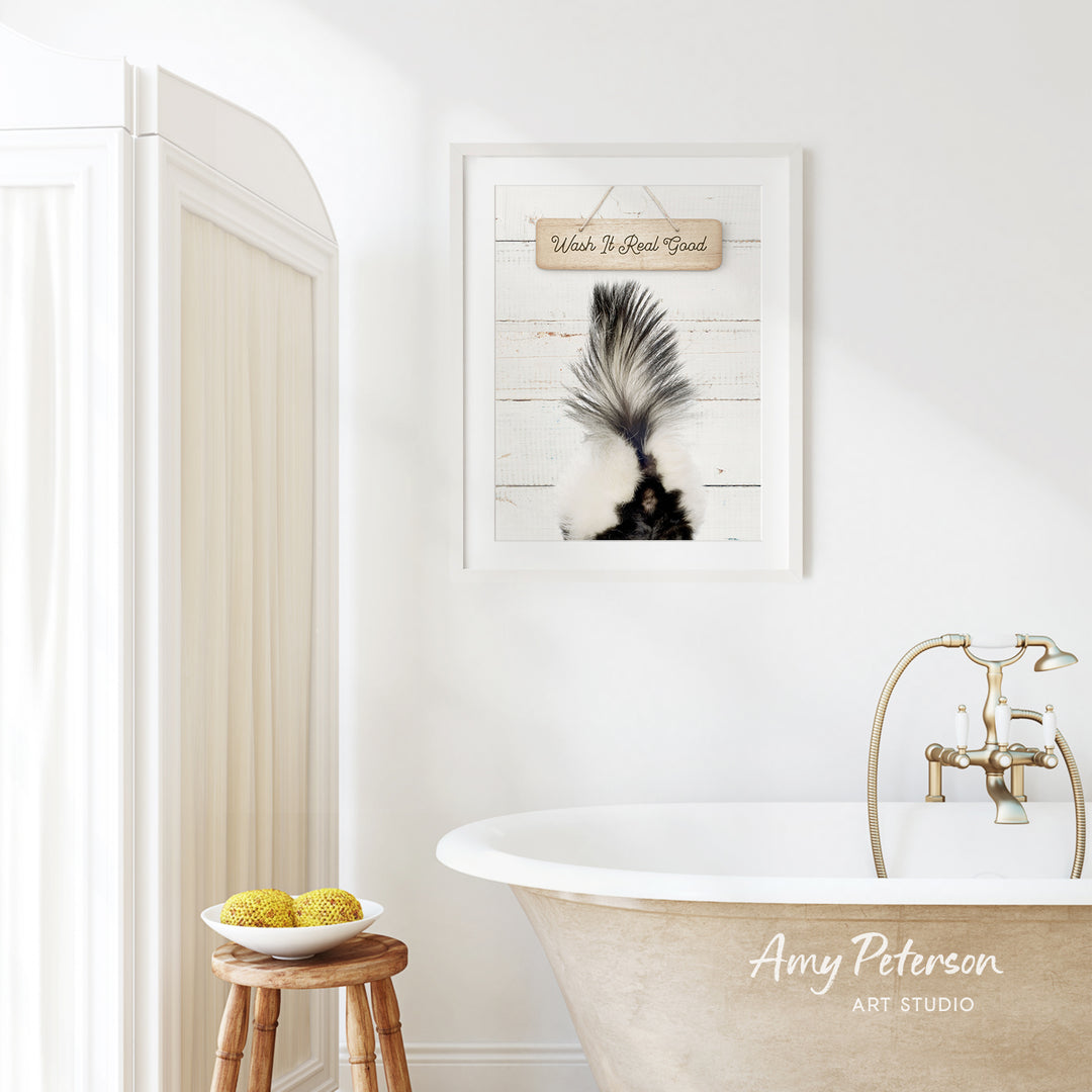 a bathroom with a white bathtub, a wooden stool, and a framed picture of a skunk on the wall.