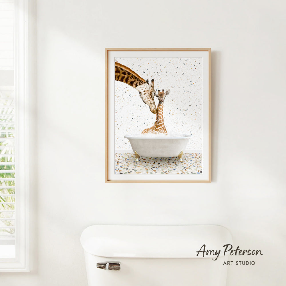 A framed painting of two giraffes in a bathtub is hanging on a white wall.
