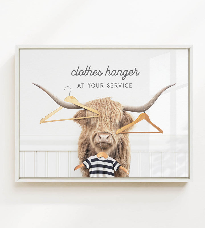 A framed image depicting a large, furry animal with long horns, wearing a striped shirt and surrounded by clothes hangers.