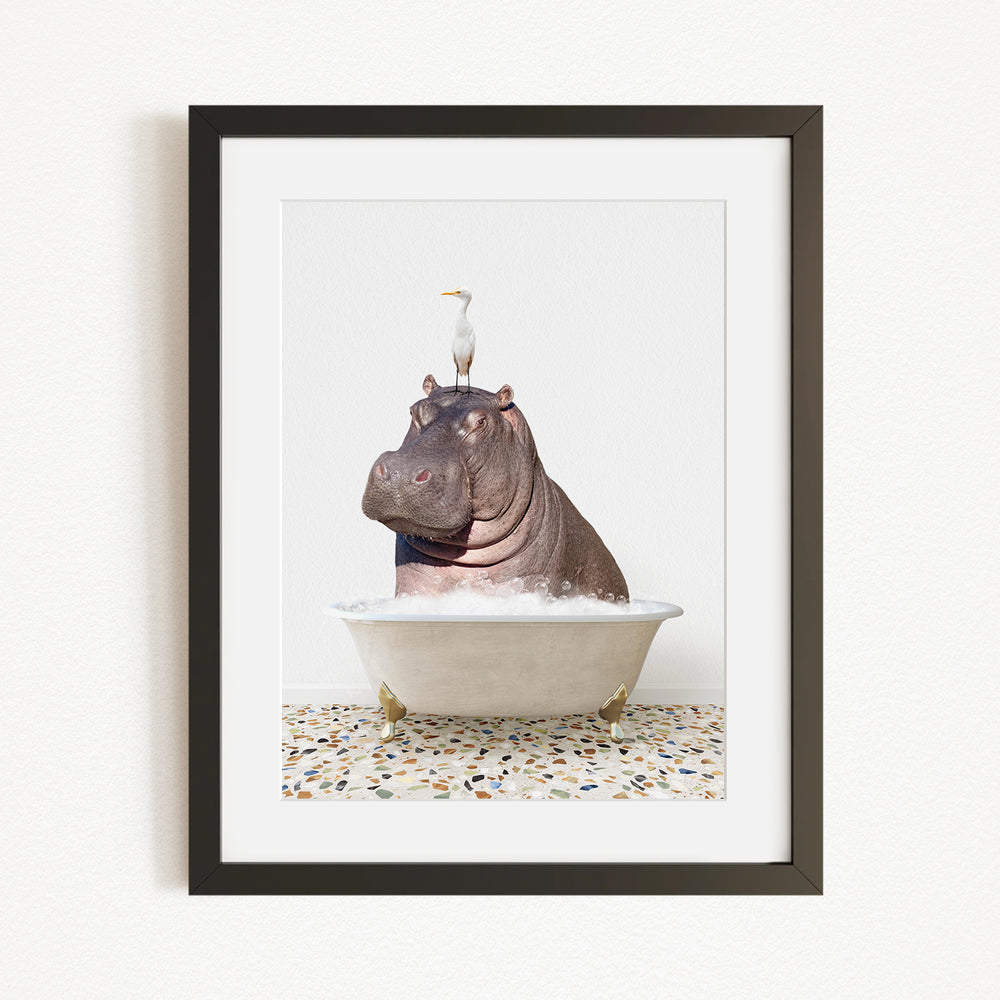 A framed image depicting a large hippopotamus sitting in a bathtub, with a seagull perched on its head.