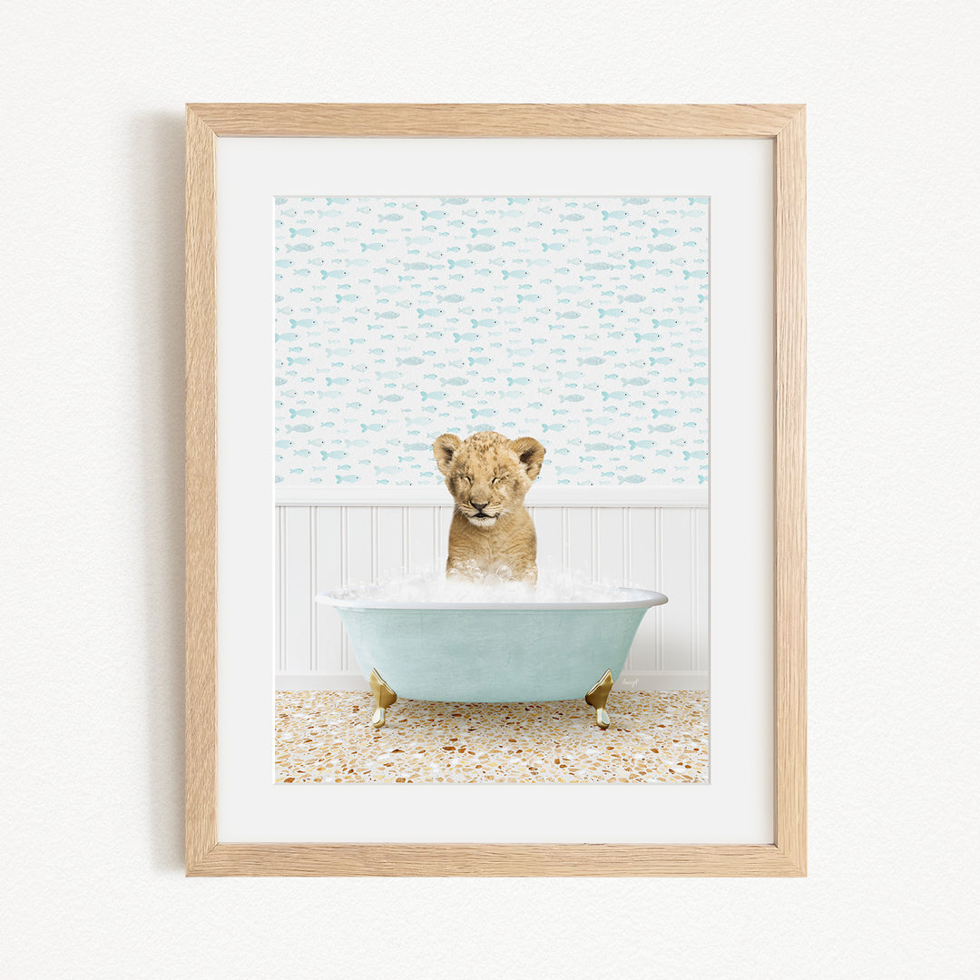A young lion cub sitting in a blue bathtub filled with water, surrounded by a patterned wall.