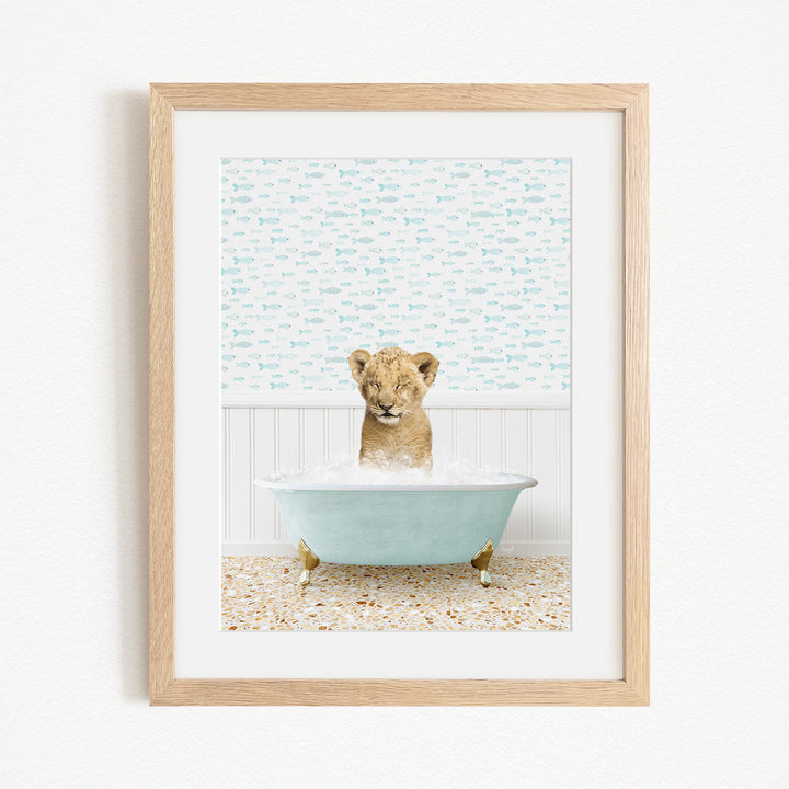 A young lion cub sitting in a blue bathtub filled with water, surrounded by a patterned wall.