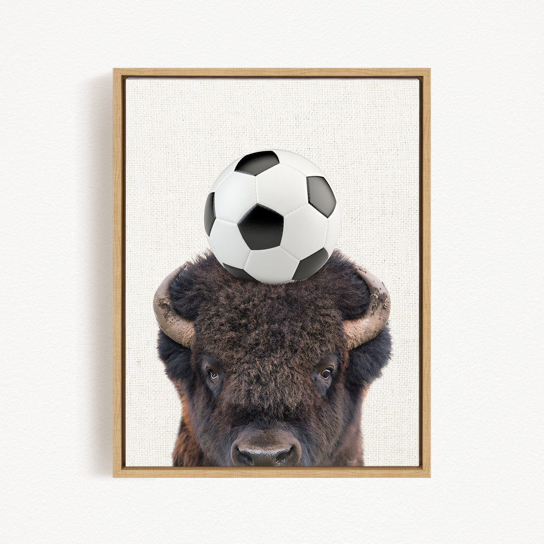 A framed image of a bison with a soccer ball on its head.