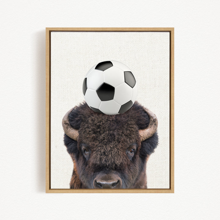 A framed image of a bison with a soccer ball on its head.