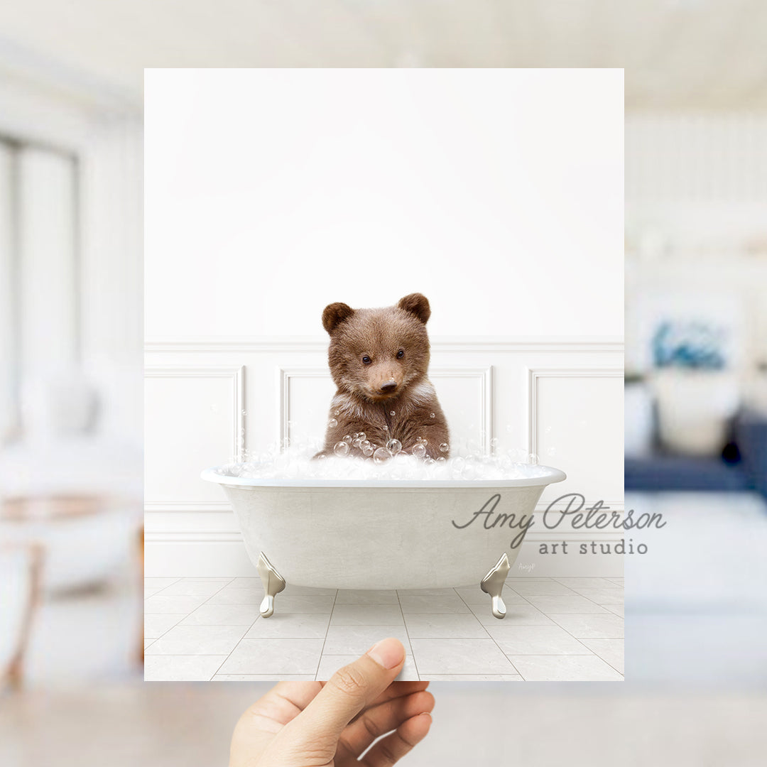 a hand holding a polaroid of a teddy bear in a bathtub