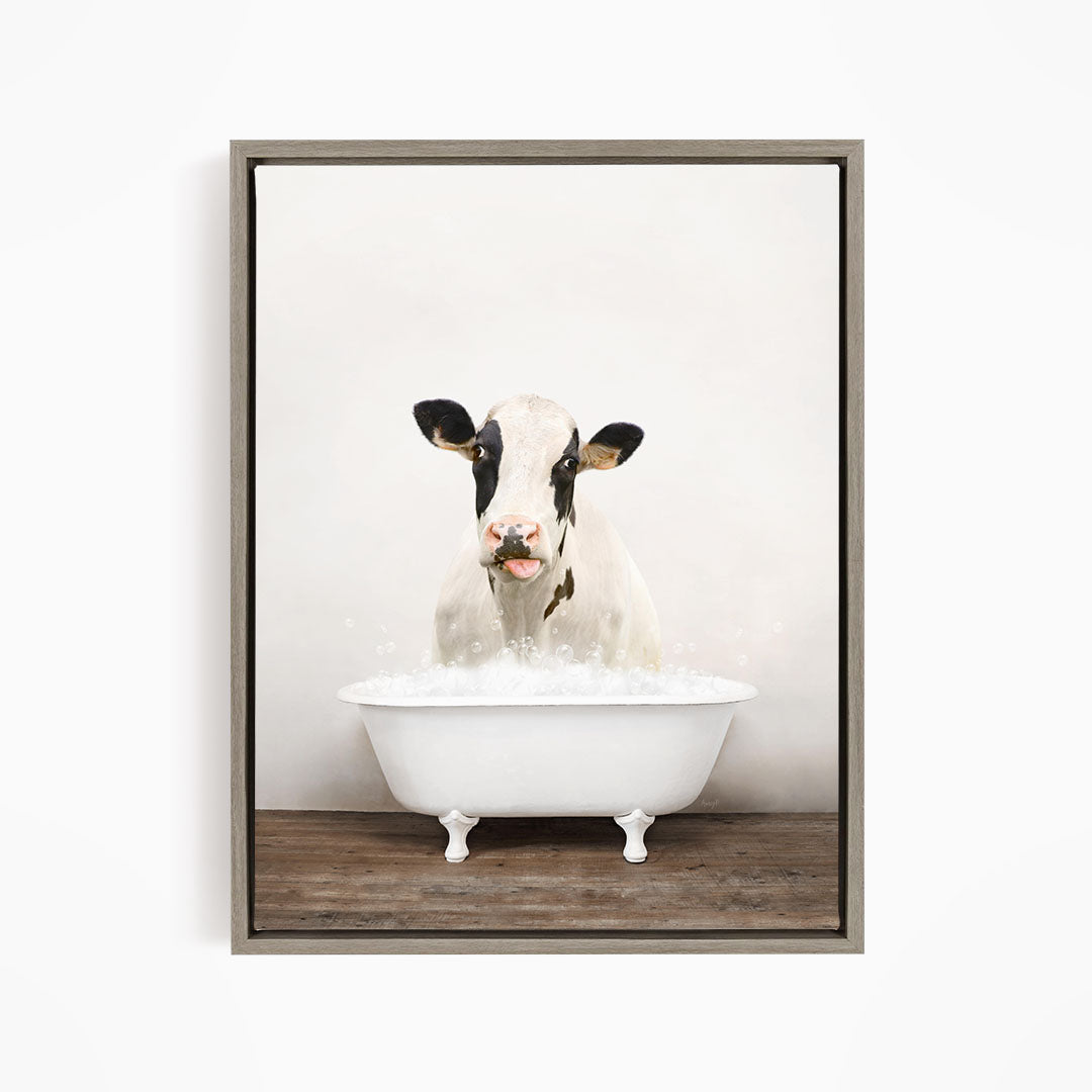 A black and white cow is sitting in a white bathtub filled with water, creating a whimsical and humorous scene.