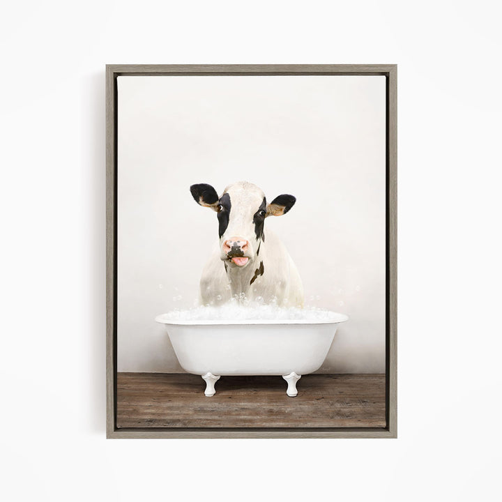 A black and white cow is sitting in a white bathtub filled with water, creating a whimsical and humorous scene.