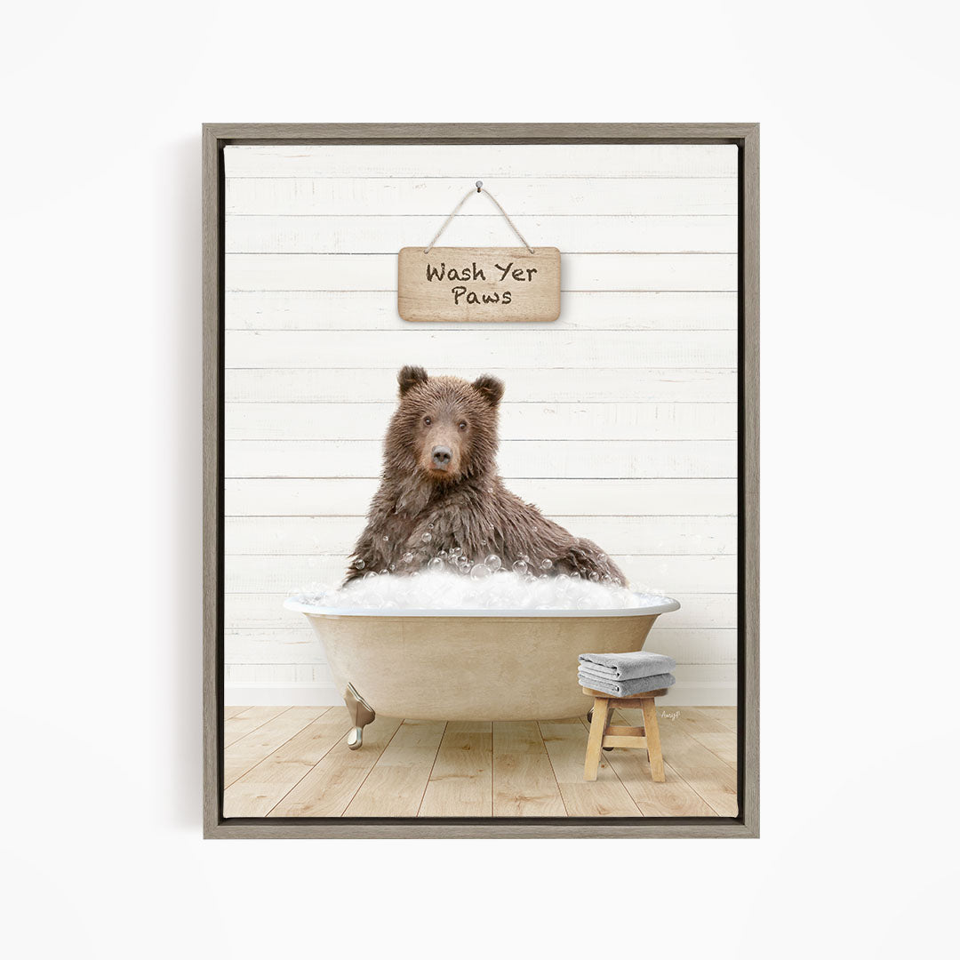 A brown bear sitting in a bathtub filled with water, with a sign above that says "Wash Your Paws".