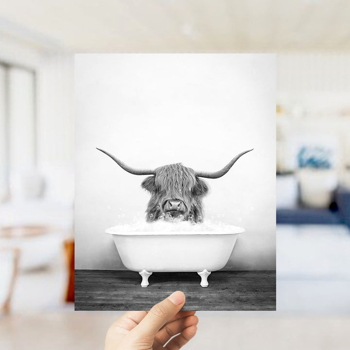 A black and white photograph of a horned animal, possibly a yak or a yak dog, sitting in a bathtub filled with water.