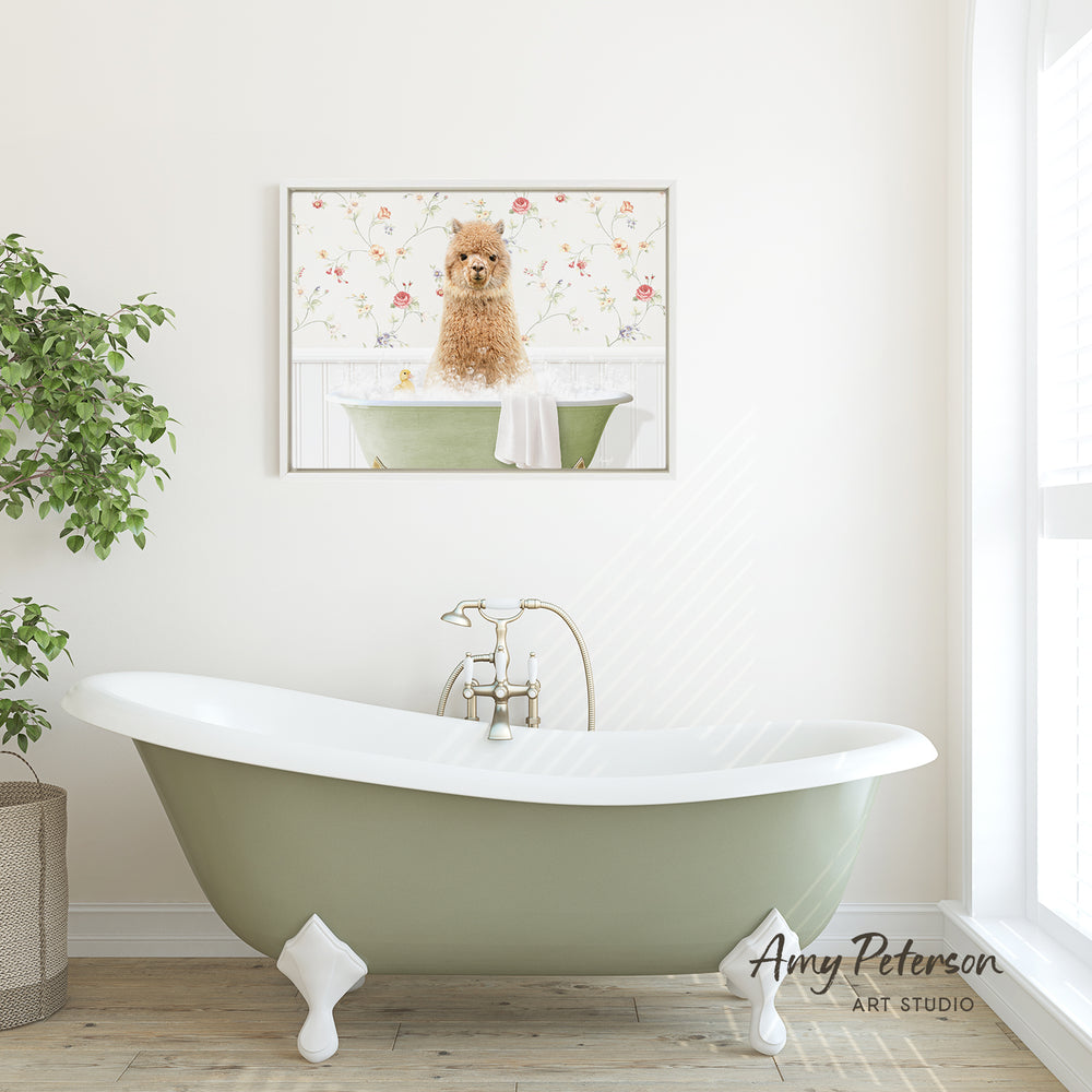 A framed image of a small dog sitting in a bathtub is displayed on the wall above a green clawfoot bathtub in a bright, white-walled bathroom.