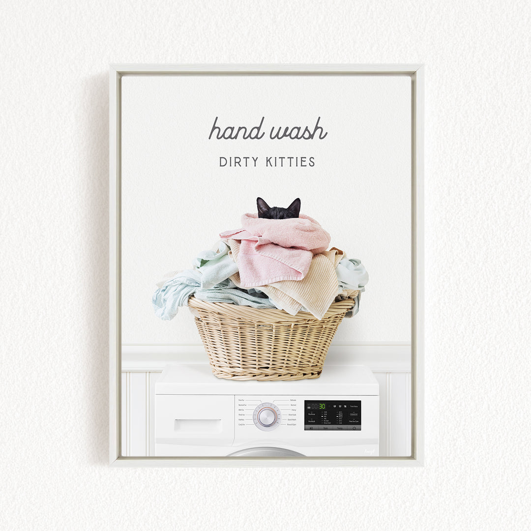 A framed image of a cat sitting in a basket filled with laundry, with the text "hand wash dirty kittens" written above it.