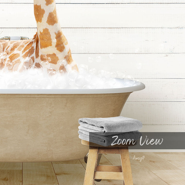 A giraffe standing in a bathtub filled with bubbles, with a towel and stool nearby.