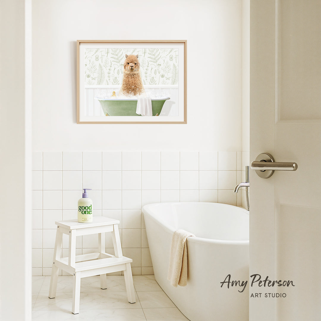 A framed image of a dog sitting in a bathtub is hanging on a white tiled wall above a white bathtub in a bathroom.