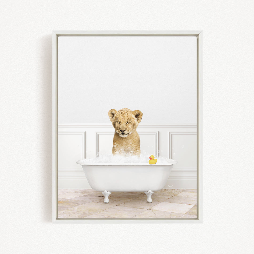 A young lion cub sitting in a white bathtub filled with bubbles, with a rubber duck floating nearby.