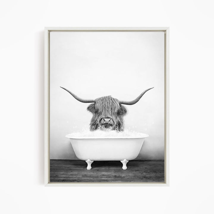 A black and white image of a horned animal, possibly a yak or a bison, sitting in a white bathtub filled with water.