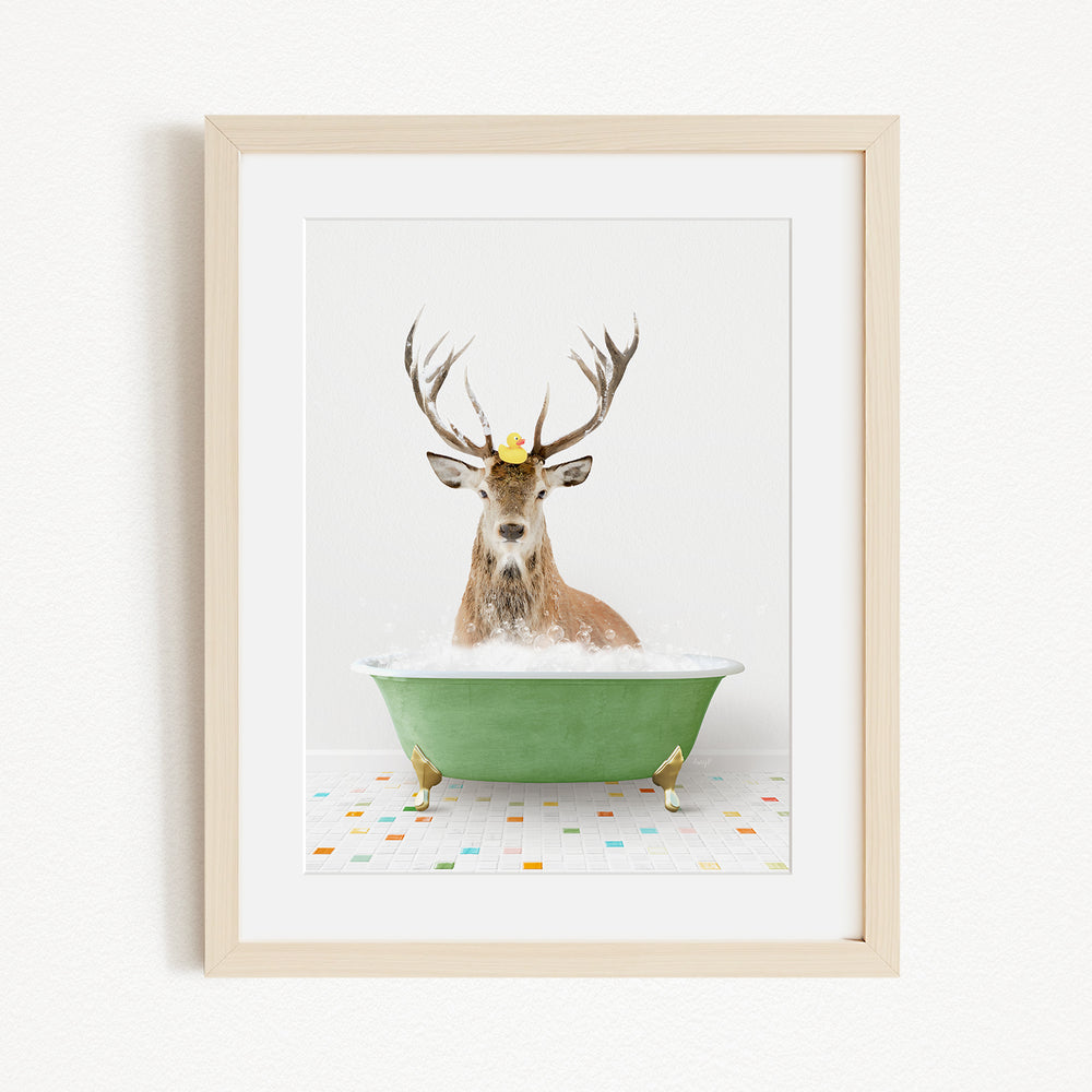 A deer with antlers is sitting in a green bathtub filled with water, with a yellow rubber duck floating on its head.