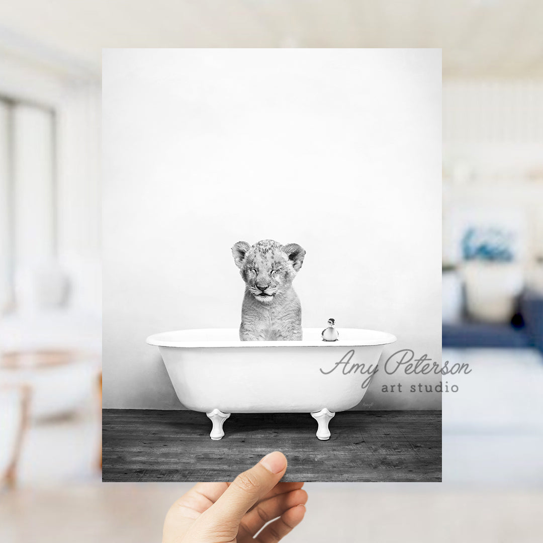 a hand holding a card with a picture of a baby tiger in a bathtub