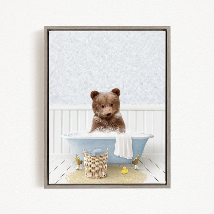 A brown bear sitting in a blue bathtub filled with water, surrounded by a yellow rubber duck and a white basket.