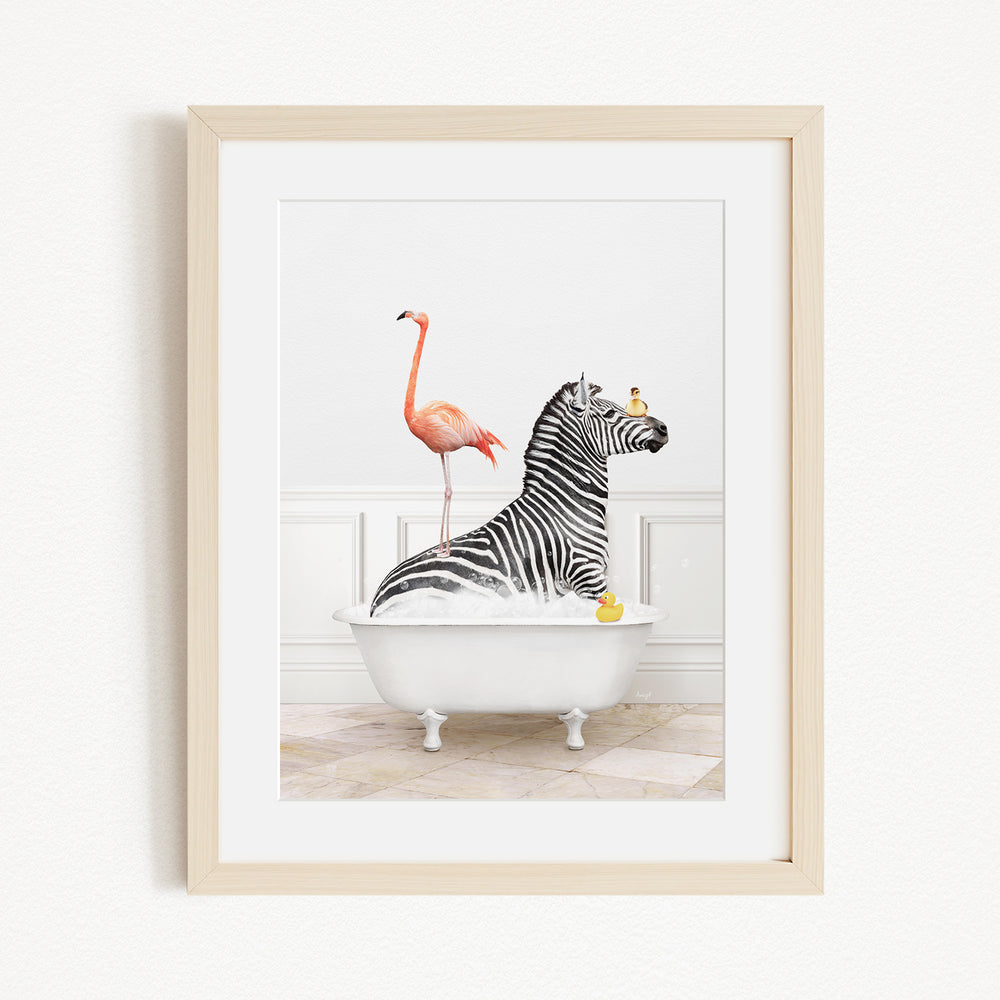 A framed image depicting a zebra sitting in a bathtub, with a flamingo standing on its back and a yellow rubber duck floating in the water.