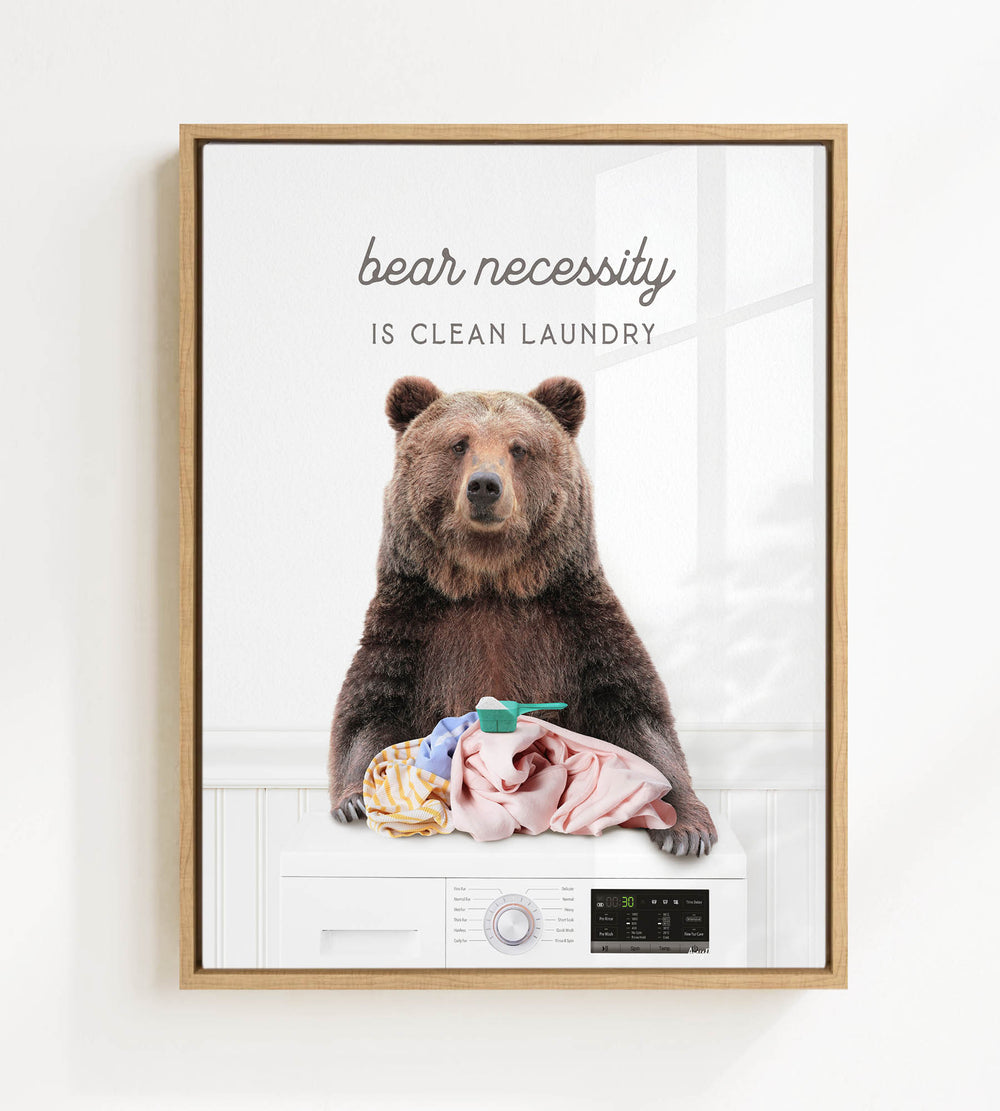 A brown bear sitting on a washing machine, with clothes hanging on the machine's door.