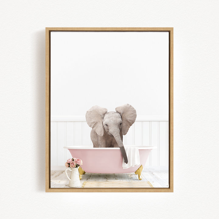 A gray elephant is sitting in a pink bathtub, surrounded by a vase of flowers and a white vase on a white wooden floor.