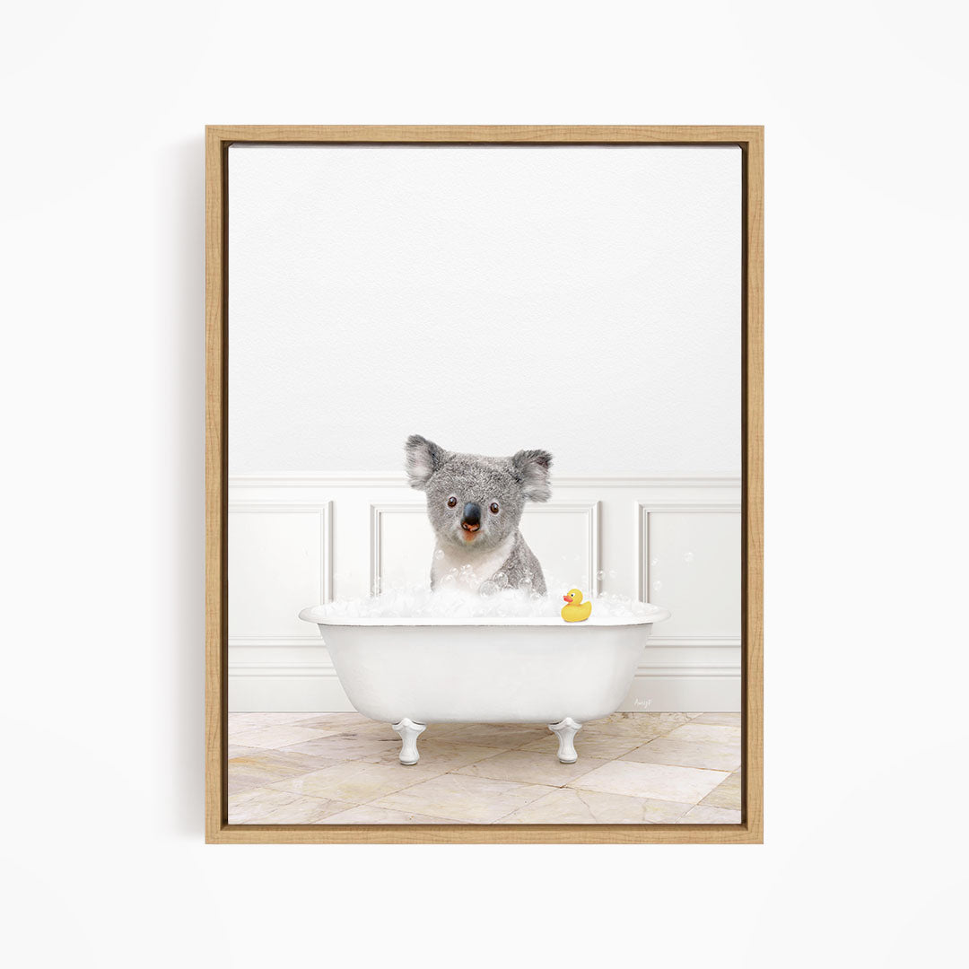 A koala bear sitting in a white bathtub filled with bubbles, with a rubber duck floating nearby.