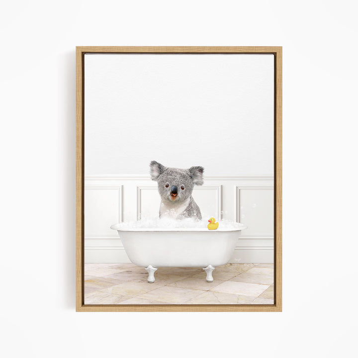 A koala bear sitting in a white bathtub filled with bubbles, with a rubber duck floating nearby.