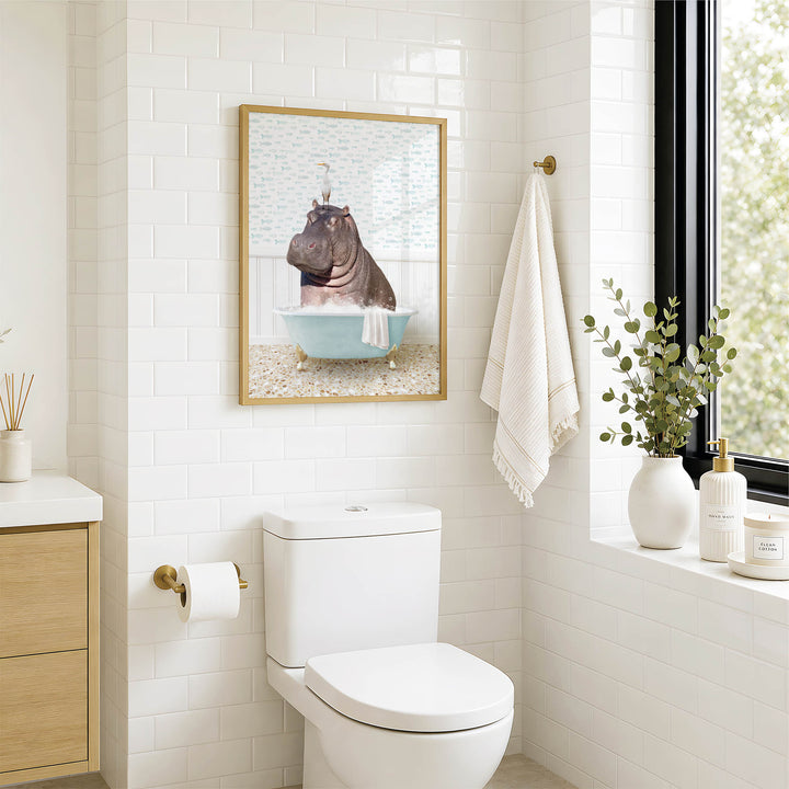 A bathroom with a white toilet, a framed picture of a hippopotamus in a bathtub, and a towel rack with a towel.