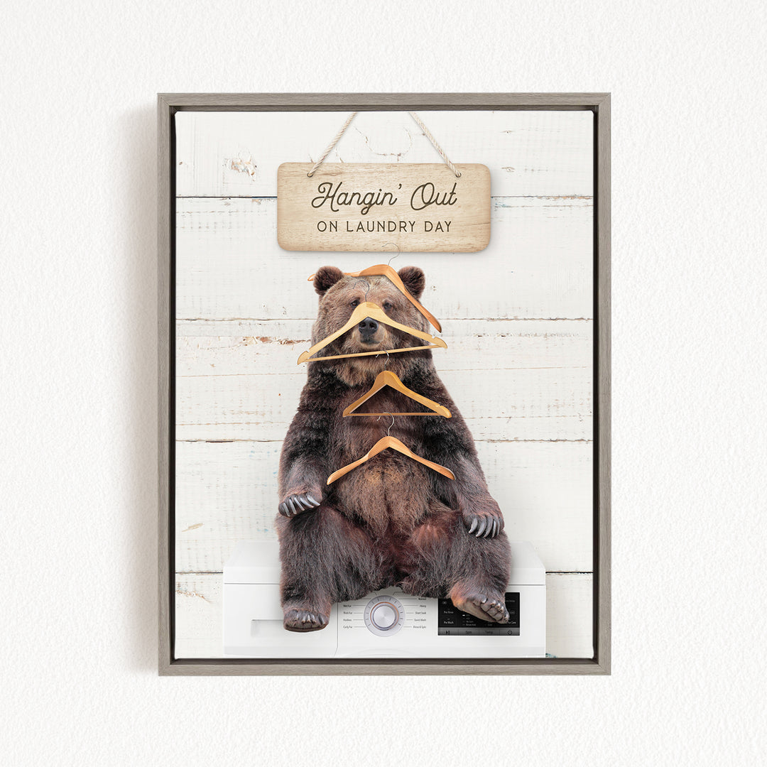 A framed image of a bear sitting on a washing machine, with a sign above it that says "Hangin' Out on laundry day".