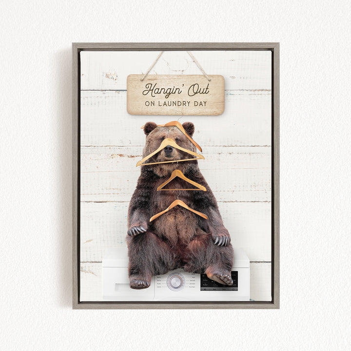 A framed image of a bear sitting on a washing machine, with a sign above it that says "Hangin' Out on laundry day".