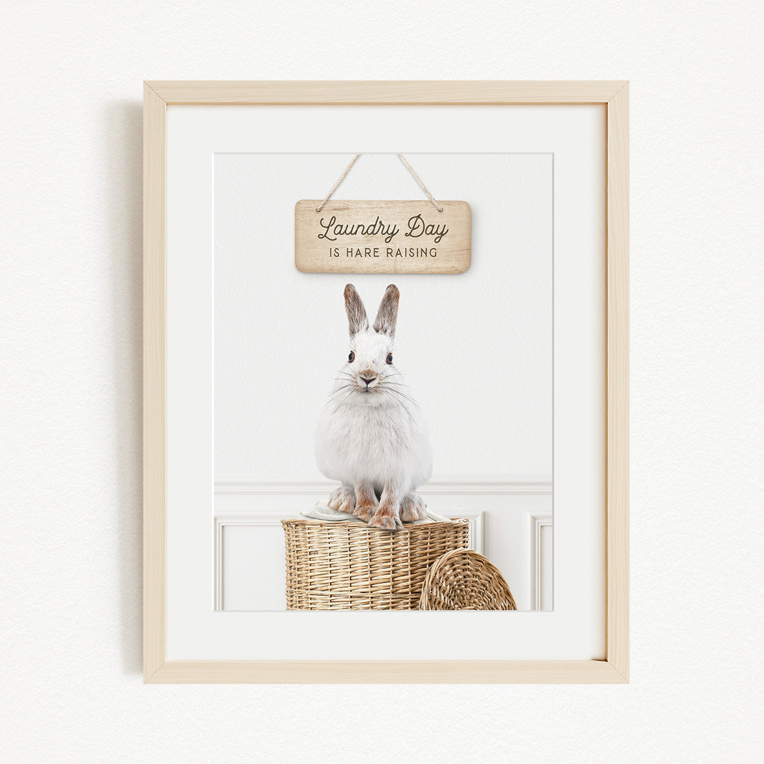 A white rabbit sitting on a wicker basket, with a wooden sign above it that says "Laundry Day is here raising".