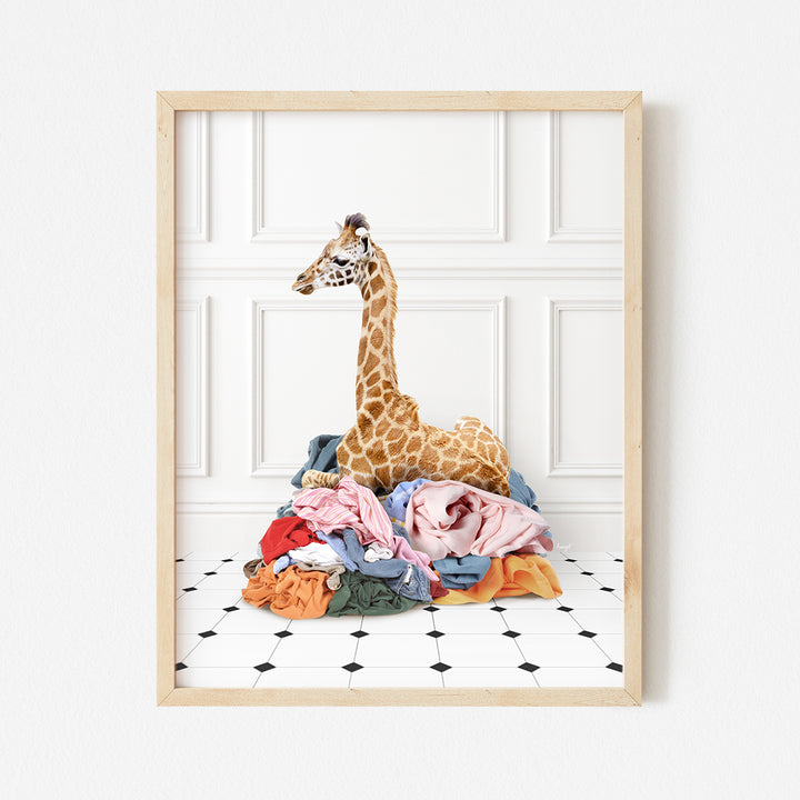 a giraffe sitting on top of a pile of clothes