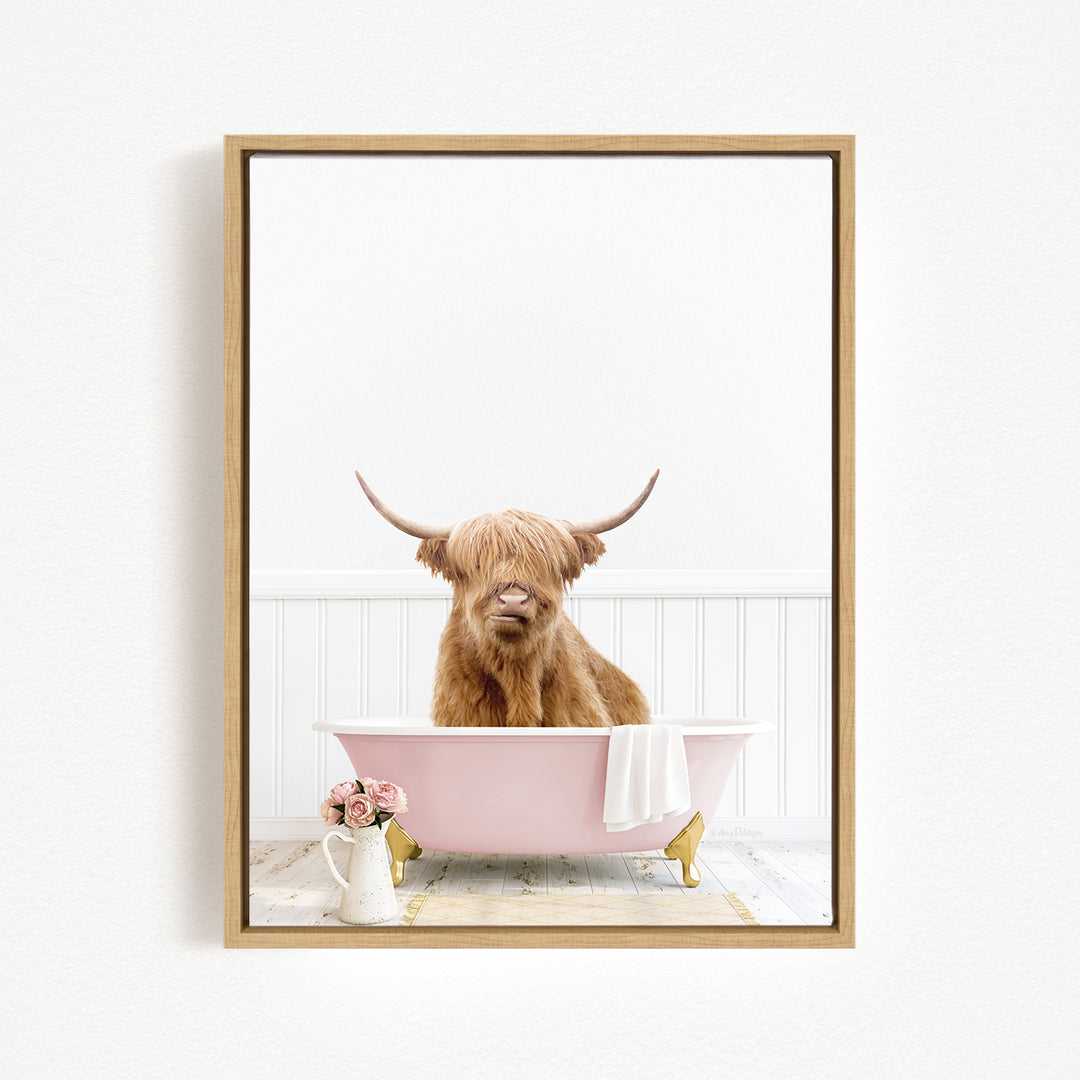 A Highland cow with long horns is sitting in a pink bathtub, surrounded by a white vase with flowers and a white towel.