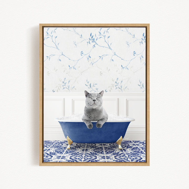 A gray cat sitting in a blue bathtub, surrounded by a patterned tile floor and a floral wallpaper background.