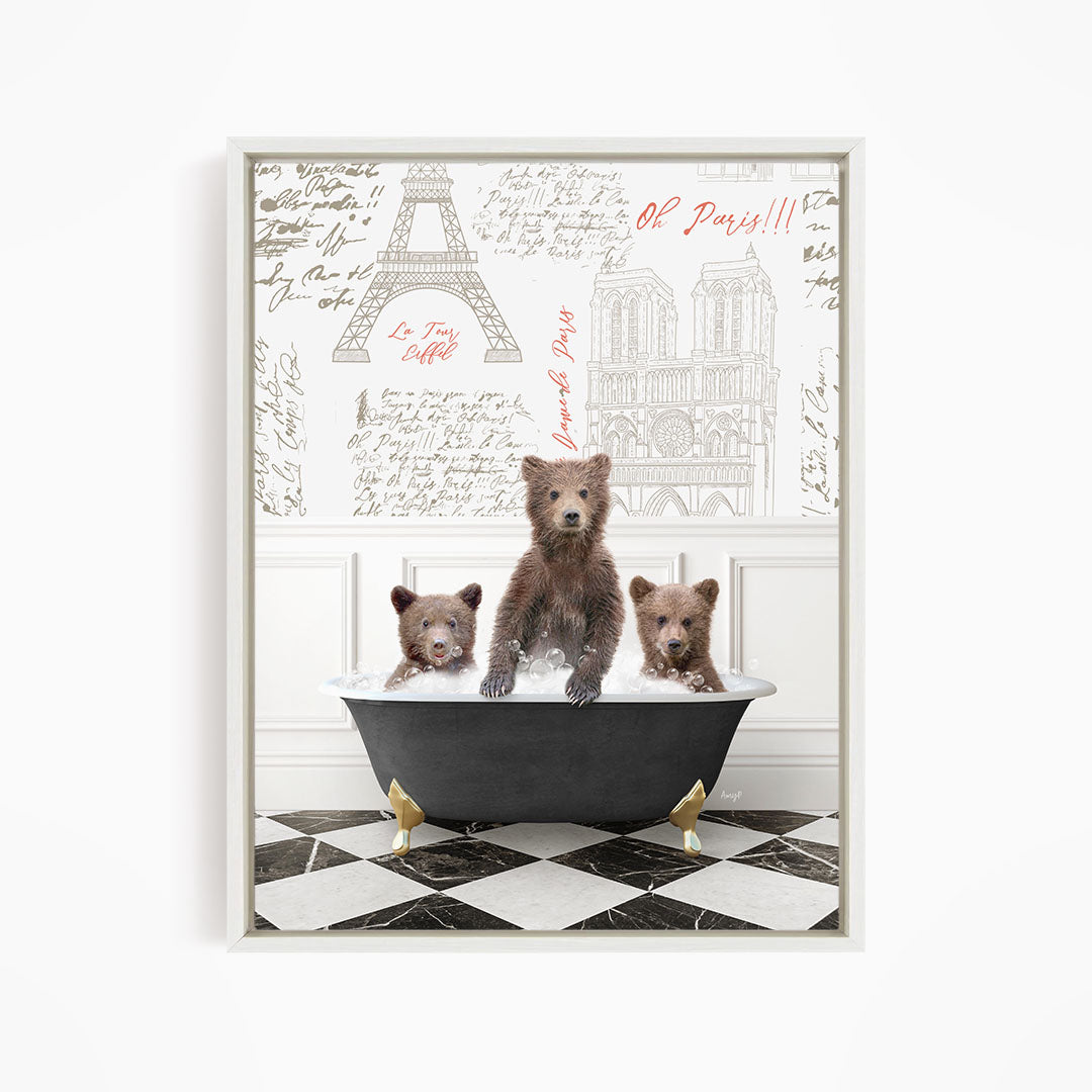 Three adorable brown bears sitting in a bathtub, with one bear sitting in the center and the other two sitting on either side. The bears appear to be enjoying a relaxing bath, and the background features a wall with various inscriptions and illustrations, including the Eiffel Tower.