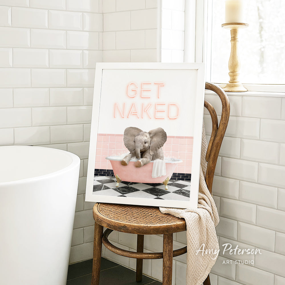 A framed print with an elephant sitting in a pink bathtub, accompanied by the text "GET NAKED" in pink letters.