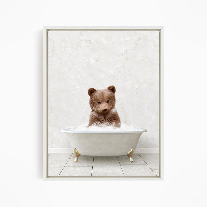A brown bear sitting in a white bathtub filled with water, looking directly at the camera.