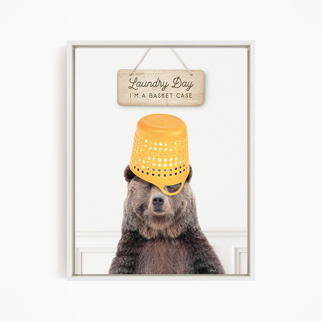 A bear wearing a yellow plastic basket on its head, with a wooden sign above that says "Laundry Day I'm a basket case".