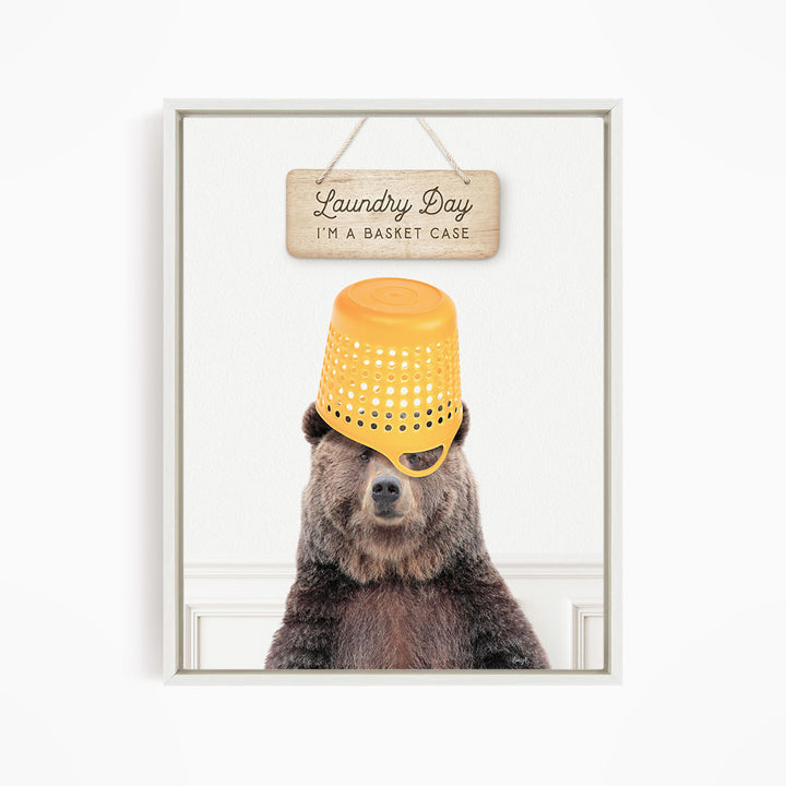 A bear wearing a yellow plastic basket on its head, with a wooden sign above that says "Laundry Day I'm a basket case".