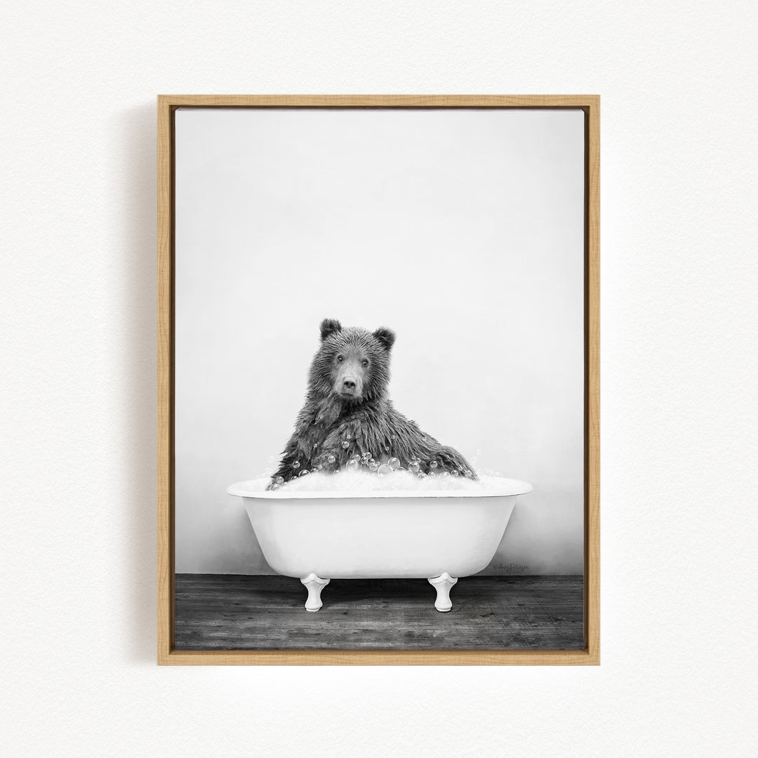 A black and white photograph of a bear sitting in a bathtub filled with water.
