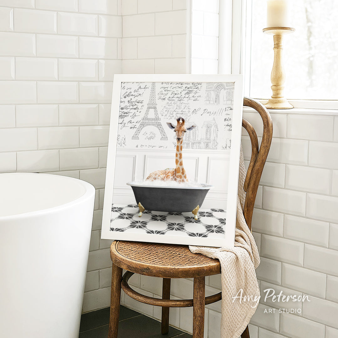 A framed image of a giraffe sitting in a bathtub, surrounded by a tiled pattern, is displayed on a wooden chair in a bathroom setting.