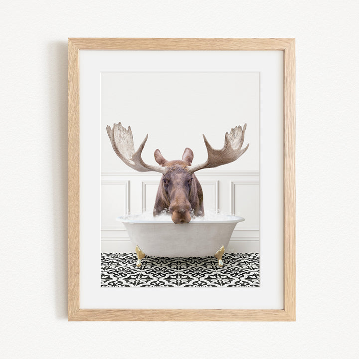 A moose with large antlers is sitting in a bathtub filled with water, creating a whimsical and humorous scene.