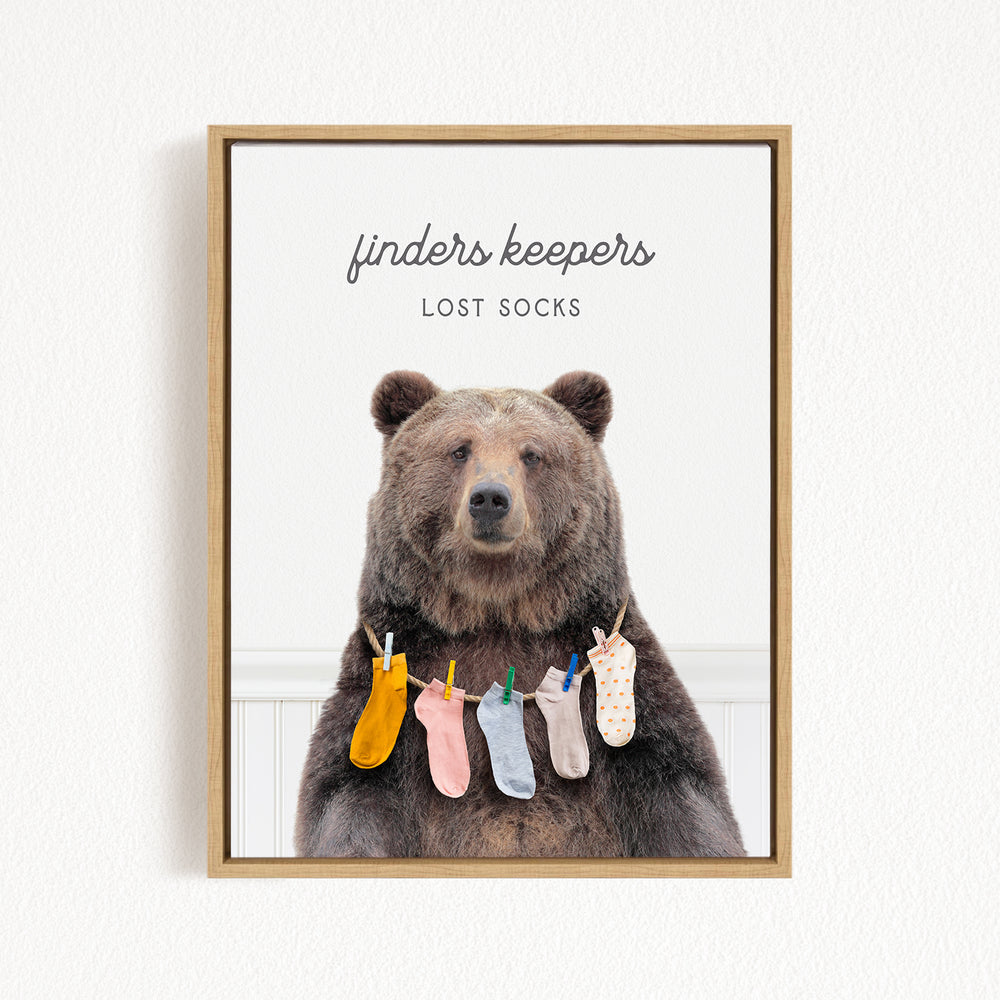 A framed image of a brown bear wearing socks, with the text "finder's keepers" and "LOST SOCKS" above the bear.