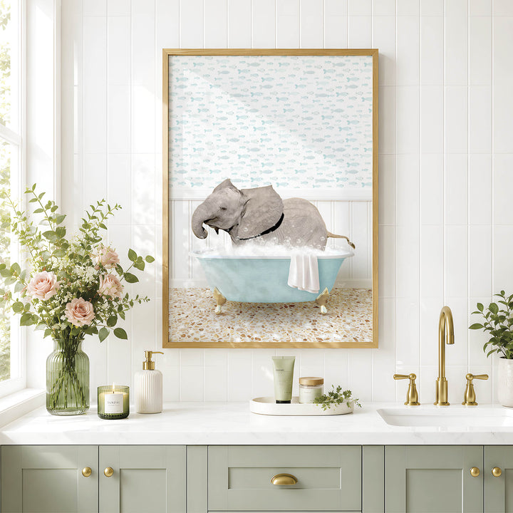 A framed image of a gray elephant sitting in a blue bathtub, surrounded by flowers and greenery, is displayed on a white tiled wall above a bathroom counter with various toiletries and a plant.