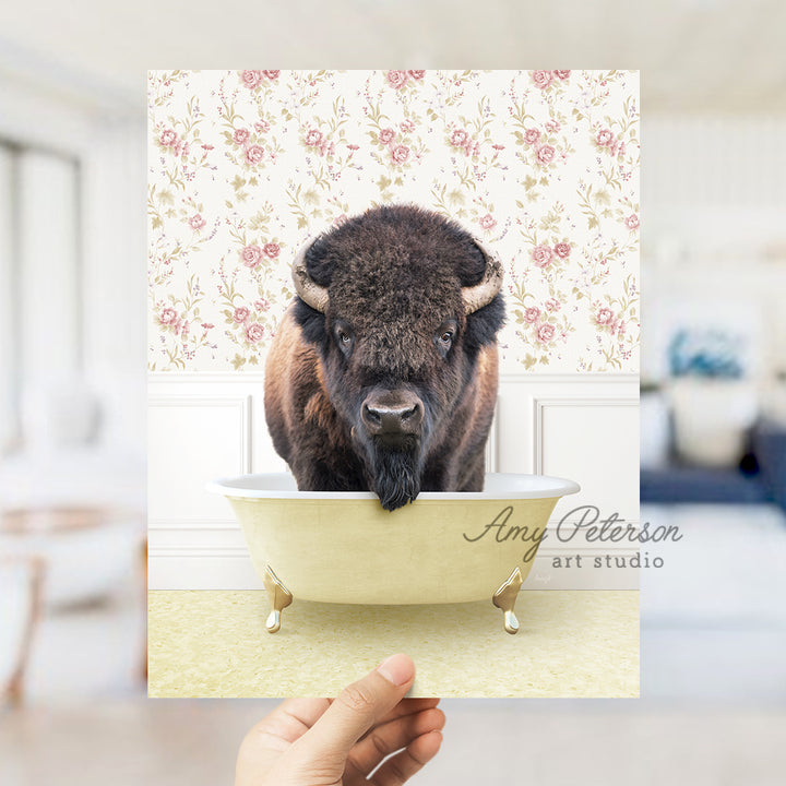 a person holding up a picture of a bison in a bathtub