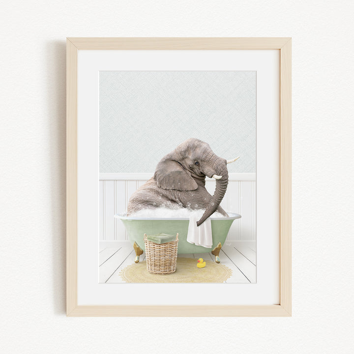 A gray elephant is sitting in a green bathtub filled with bubbles, surrounded by a yellow rubber duck and a basket.